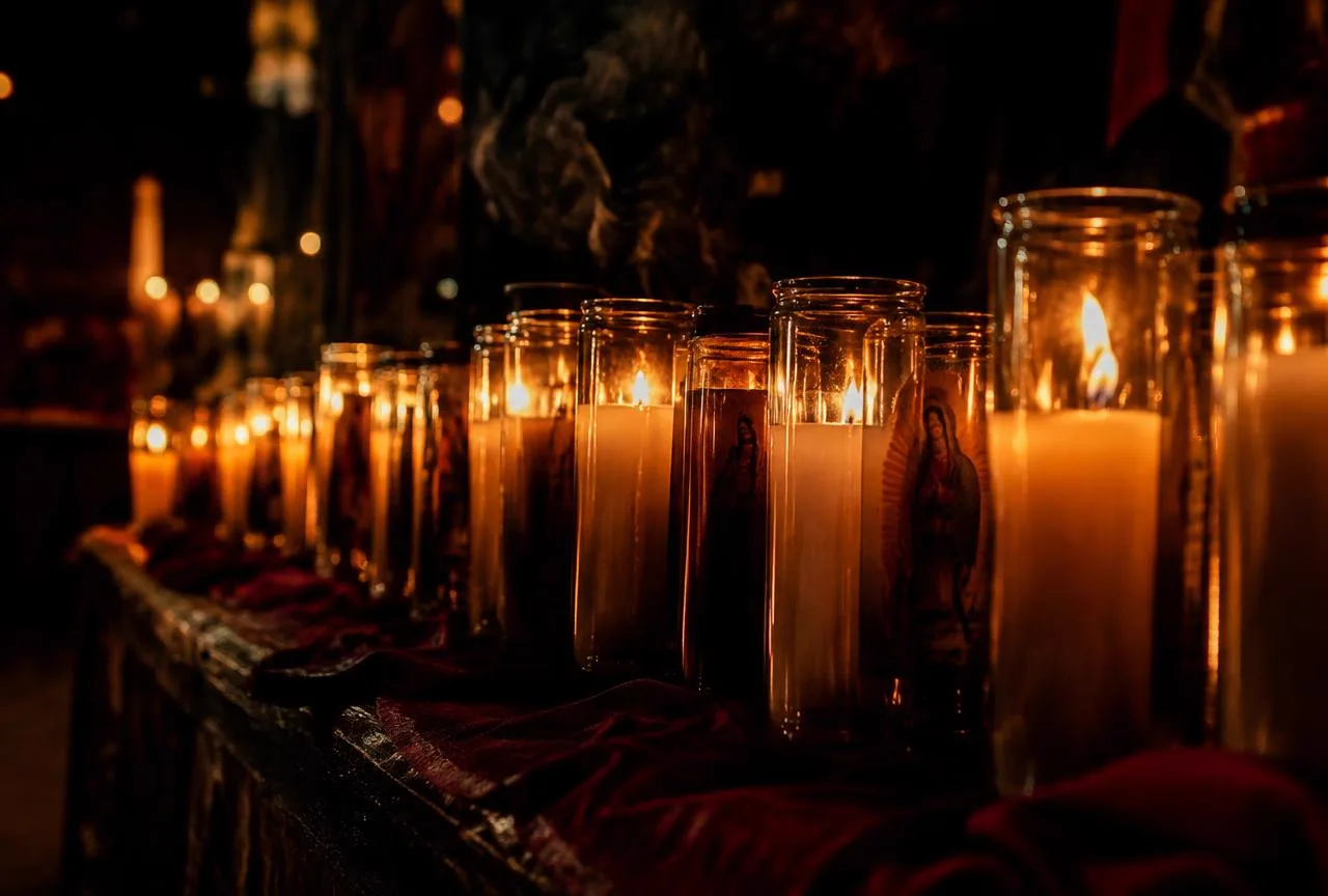 Hileras de veladoras encendidas en la penumbra